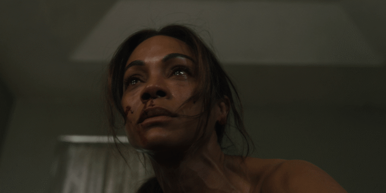 Close-up of an injured woman with tears in her eyes, looking upward in a dimly lit room during Lioness Season 3.